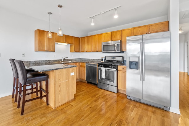 4537 S Drexel Blvd Unit 504, Chicago, IL 60653 - kitchen with stainless steel appliances, a peninsula, light wood-style floors, dark stone countertops, and hanging light fixtures