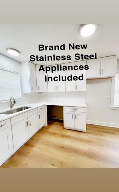 132 W 126th Pl, Chicago, IL 60628 - kitchen featuring white cabinets, light wood-style flooring, and light countertops