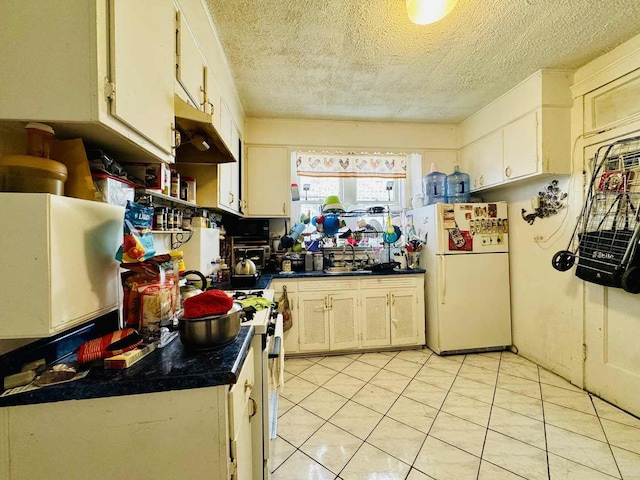 5221 W Montrose Ave, Chicago, IL 60641 - kitchen featuring freestanding refrigerator, dark countertops, under cabinet range hood, range with gas stovetop, and white cabinets