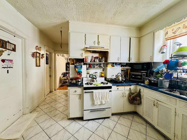 5221 W Montrose Ave, Chicago, IL 60641 - kitchen with white gas range oven, under cabinet range hood, a textured ceiling, dark countertops, and light tile patterned flooring