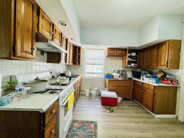 5221 W Montrose Ave, Chicago, IL 60641 - kitchen featuring under cabinet range hood, open shelves, light wood-type flooring, and white range with gas stovetop