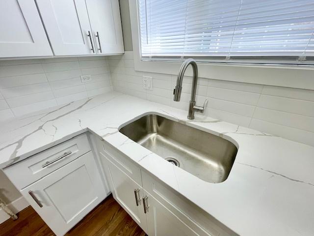10049 S Calhoun Ave, Chicago, IL 60617 - kitchen with decorative backsplash, white cabinetry, dark wood finished floors, and light stone countertops