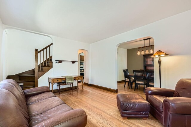 4017 Park Ave, Brookfield, IL 60513 - living room featuring arched walkways, light wood-style flooring, and stairs