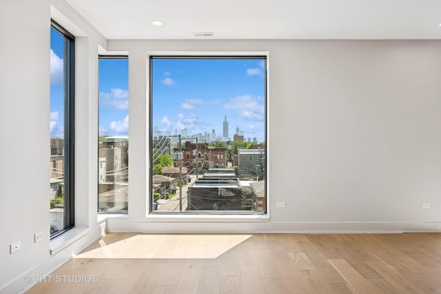 222 S Oakley Blvd Unit 3, Chicago, IL 60612 - spare room with wood finished floors, a view of skyline, and recessed lighting