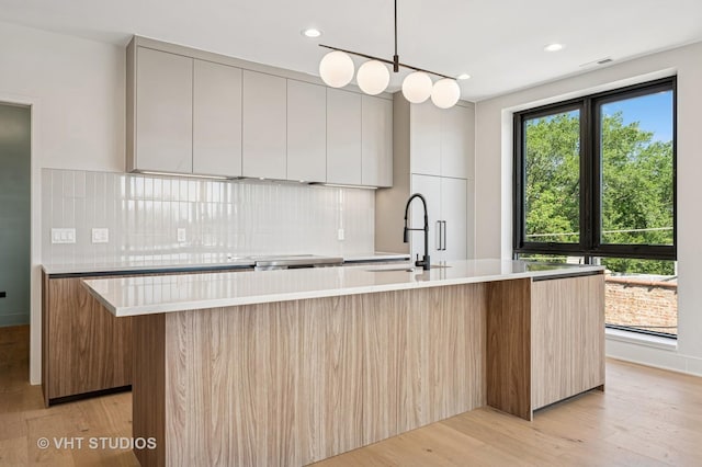 222 S Oakley Blvd Unit 3, Chicago, IL 60612 - kitchen with modern cabinets, a large island with sink, decorative backsplash, light countertops, and recessed lighting