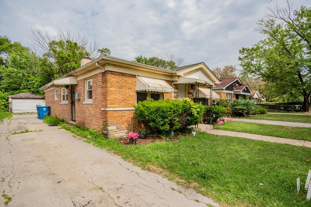 15533 Vincennes Rd, Phoenix, IL 60426 - bungalow featuring a chimney, brick siding, an outbuilding, a front yard, and a garage