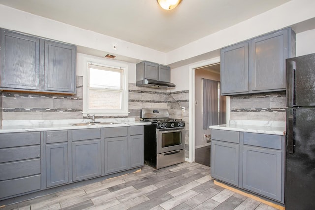 15533 Vincennes Rd, Phoenix, IL 60426 - kitchen with stainless steel gas range, freestanding refrigerator, gray cabinets, decorative backsplash, and light countertops
