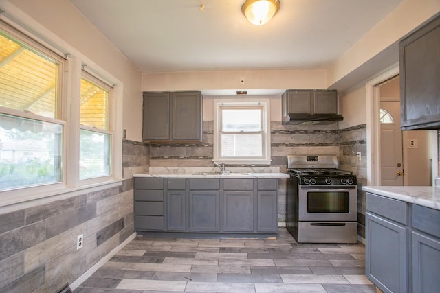 15533 Vincennes Rd, Phoenix, IL 60426 - kitchen featuring stainless steel gas range, light countertops, gray cabinetry, under cabinet range hood, and light wood-style floors