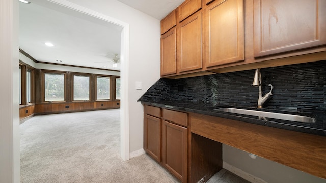 5809 Inverness Dr, Rockford, IL 61107 - kitchen with light carpet, backsplash, ceiling fan, brown cabinetry, and crown molding