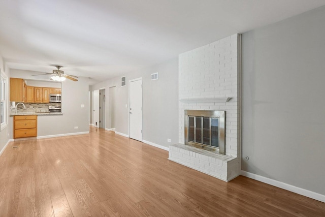 32 Woodridge Ln, Streamwood, IL 60107 - unfurnished living room with light wood-style floors, a ceiling fan, and a brick fireplace