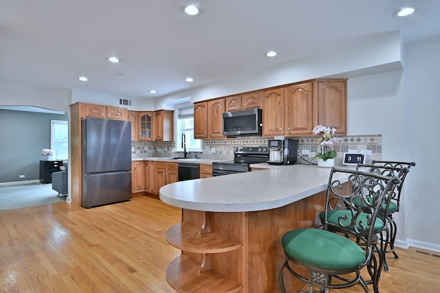 1747 Linneman St, Glenview, IL 60025 - kitchen featuring black appliances, a peninsula, light countertops, brown cabinetry, and recessed lighting