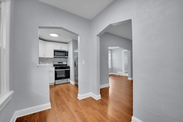 305 S Lewis Ave, Waukegan, IL 60085 - hall with light wood-style flooring, arched walkways, and a textured wall