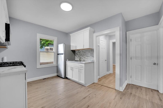 305 S Lewis Ave, Waukegan, IL 60085 - kitchen featuring freestanding refrigerator, light wood-type flooring, white cabinets, tasteful backsplash, and range with gas cooktop