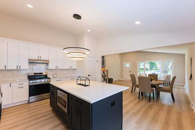 570 Dawes Ave, Glen Ellyn, IL 60137 - kitchen featuring appliances with stainless steel finishes, under cabinet range hood, white cabinets, light countertops, and a kitchen island