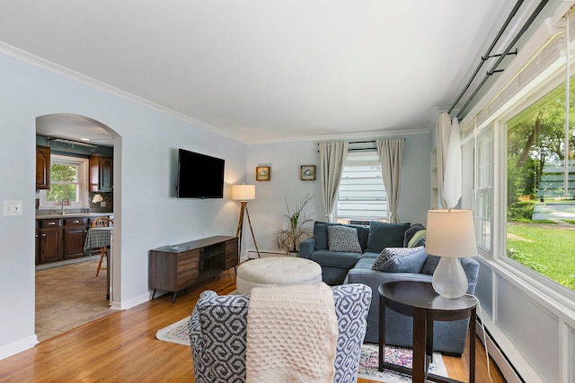 49 Burton Ave, Cary, IL 60013 - living room with a baseboard heating unit, crown molding, arched walkways, healthy amount of natural light, and light wood-style floors