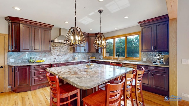 19113 Lauren Ln, Marengo, IL 60152 - kitchen featuring light wood-type flooring, wall chimney exhaust hood, a kitchen island, decorative light fixtures, and recessed lighting
