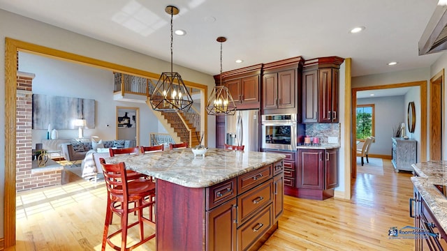 19113 Lauren Ln, Marengo, IL 60152 - kitchen with appliances with stainless steel finishes, open floor plan, light wood-style flooring, recessed lighting, and a breakfast bar