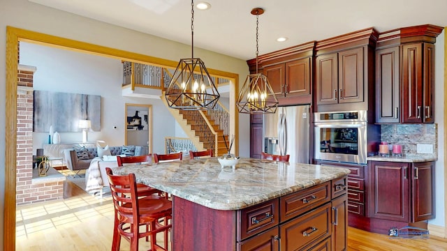 19113 Lauren Ln, Marengo, IL 60152 - kitchen with stainless steel appliances, a chandelier, open floor plan, a kitchen bar, and light wood-style floors