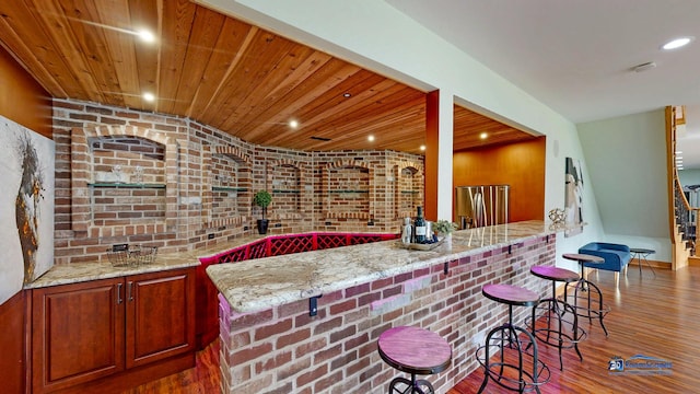 19113 Lauren Ln, Marengo, IL 60152 - kitchen featuring stainless steel fridge with ice dispenser, wood finished floors, light stone counters, a breakfast bar, and brick wall