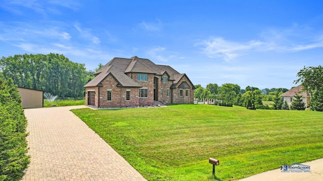 19113 Lauren Ln, Marengo, IL 60152 - french country style house featuring brick siding, decorative driveway, a front lawn, and an attached garage