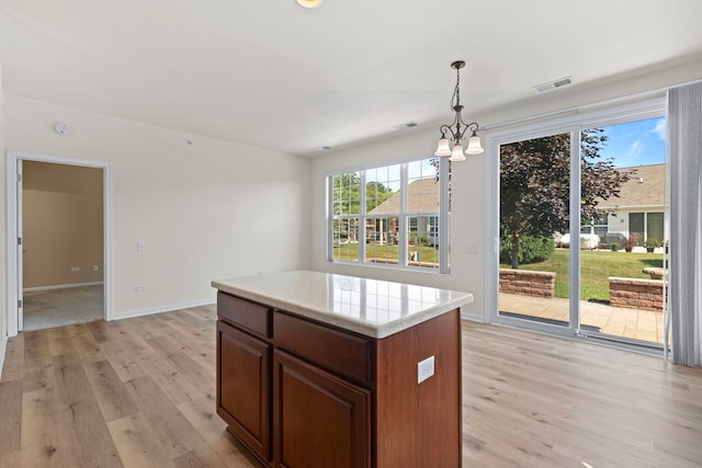 14300 Sundance Dr, Huntley, IL 60142 - kitchen with light wood finished floors, light countertops, decorative light fixtures, a center island, and a chandelier