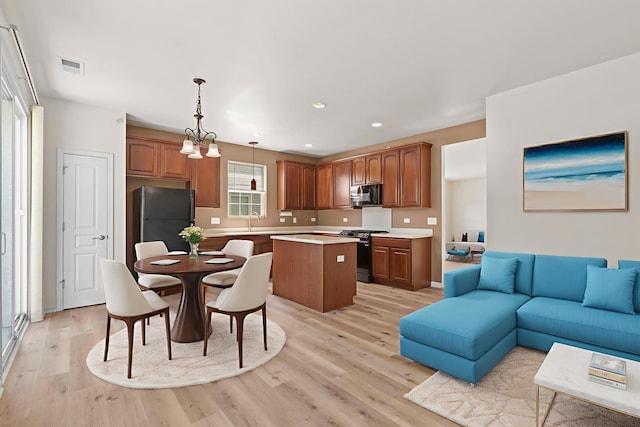 14300 Sundance Dr, Huntley, IL 60142 - kitchen with black appliances, a kitchen island, open floor plan, light wood-style flooring, and light countertops
