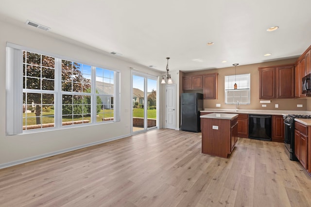 14300 Sundance Dr, Huntley, IL 60142 - kitchen featuring black appliances, a center island, light countertops, light wood-style flooring, and plenty of natural light
