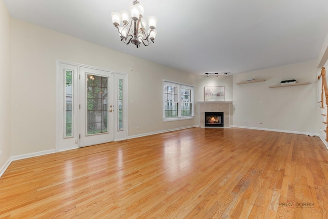 1804 Monroe Ct, Glenview, IL 60025 - unfurnished living room with a chandelier, light wood-style floors, a fireplace with flush hearth, and rail lighting