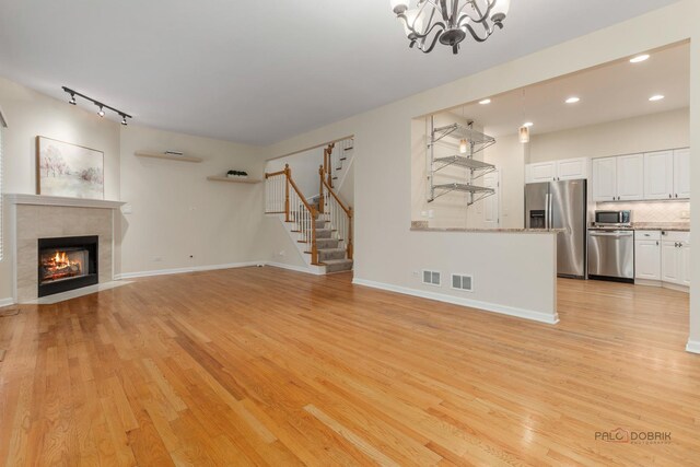 1804 Monroe Ct, Glenview, IL 60025 - unfurnished living room with light wood finished floors, a chandelier, recessed lighting, a fireplace, and stairway