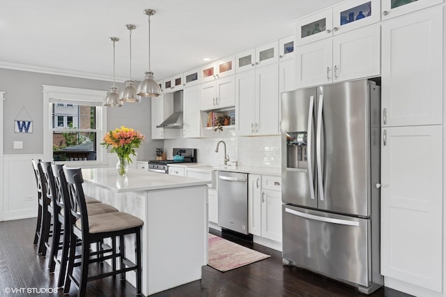 5106 W Eddy St, Chicago, IL 60641 - kitchen featuring stainless steel appliances, wall chimney exhaust hood, dark wood-style flooring, a kitchen island, and white cabinets