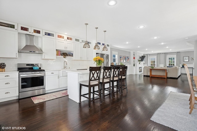 5106 W Eddy St, Chicago, IL 60641 - kitchen with stainless steel appliances, wall chimney range hood, light countertops, a center island, and a kitchen bar