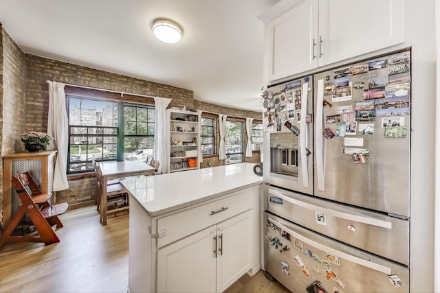7021 N Sheridan Rd Unit 1, Chicago, IL 60626 - kitchen with stainless steel refrigerator with ice dispenser, a peninsula, brick wall, white cabinets, and light countertops