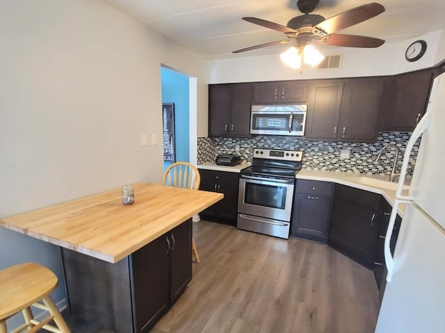 11009 Stony Creek Dr Unit 1C, Palos Hills, IL 60465 - kitchen featuring appliances with stainless steel finishes, a breakfast bar, decorative backsplash, wood finished floors, and ceiling fan