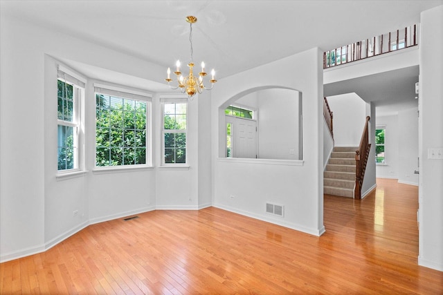 270 Birch Ln, Saint Charles, IL 60175 - unfurnished dining area with hardwood / wood-style flooring, a chandelier, stairs, and arched walkways