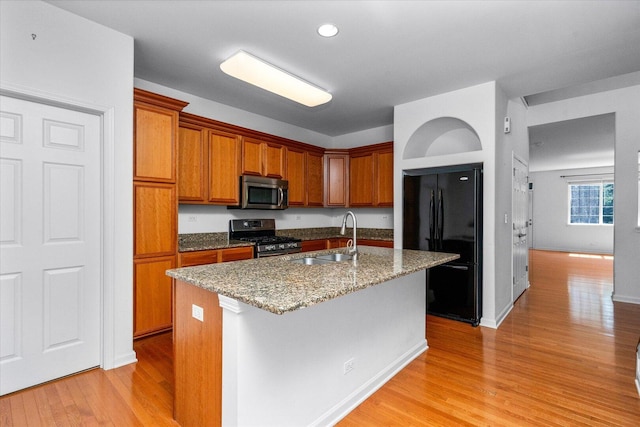 270 Birch Ln, Saint Charles, IL 60175 - kitchen with stainless steel appliances, light wood-type flooring, brown cabinetry, light stone countertops, and an island with sink