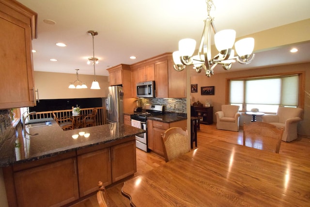 963 E Castlewood Ln, Bartlett, IL 60103 - kitchen with appliances with stainless steel finishes, a chandelier, light wood-type flooring, backsplash, and dark stone counters