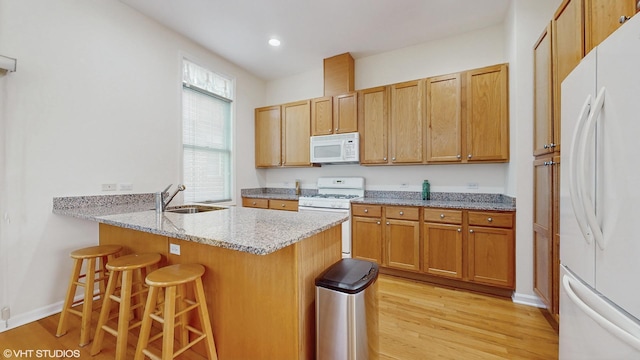 4606 S Woodlawn Ave, Chicago, IL 60653 - kitchen with white appliances, a kitchen bar, light wood-style flooring, light stone counters, and a peninsula