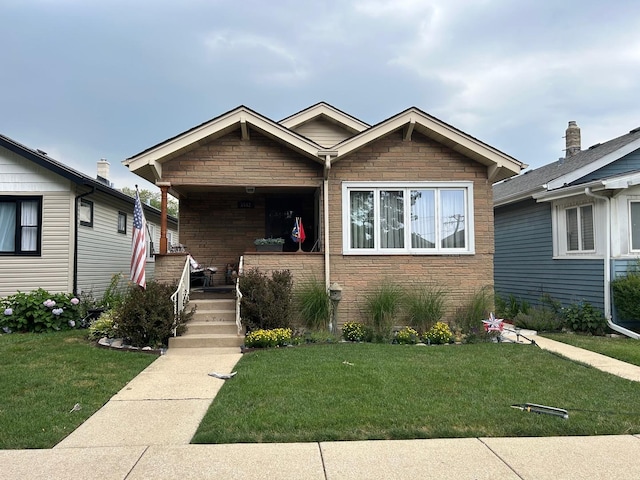 5542 W Grace St, Chicago, IL 60641 - view of front of house featuring a front lawn, stone siding, and covered porch
