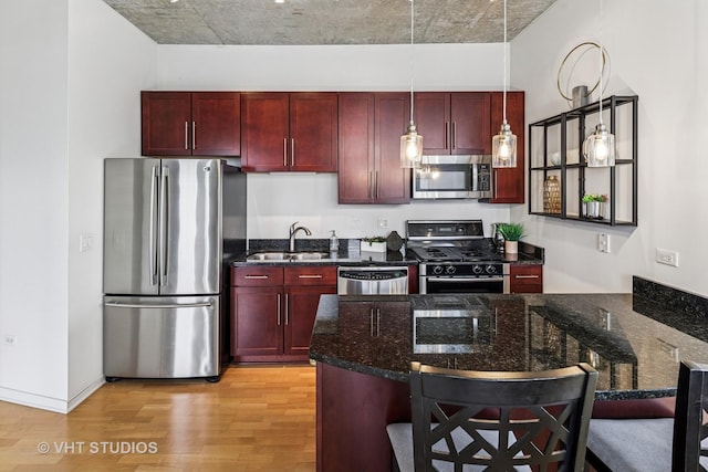 700 N Larrabee St Unit 1409, Chicago, IL 60654 - kitchen with stainless steel appliances, reddish brown cabinets, light wood-style floors, dark stone countertops, and a kitchen breakfast bar