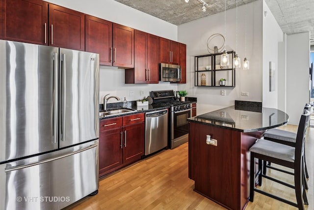 700 N Larrabee St Unit 1409, Chicago, IL 60654 - kitchen featuring appliances with stainless steel finishes, reddish brown cabinets, light wood-type flooring, a peninsula, and rail lighting