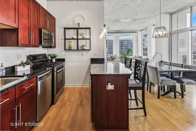 700 N Larrabee St Unit 1409, Chicago, IL 60654 - kitchen with reddish brown cabinets, appliances with stainless steel finishes, light wood-style floors, and dark stone counters