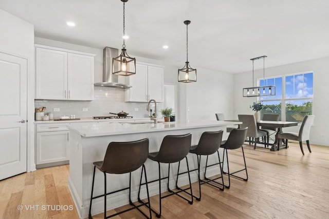 1140 River Birch Blvd, Crystal Lake, IL 60012 - kitchen featuring wall chimney exhaust hood, backsplash, a breakfast bar, light wood finished floors, and white cabinetry