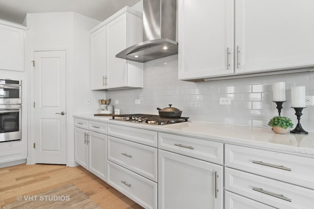 1140 River Birch Blvd, Crystal Lake, IL 60012 - kitchen with wall chimney range hood, appliances with stainless steel finishes, light wood-style flooring, and white cabinets