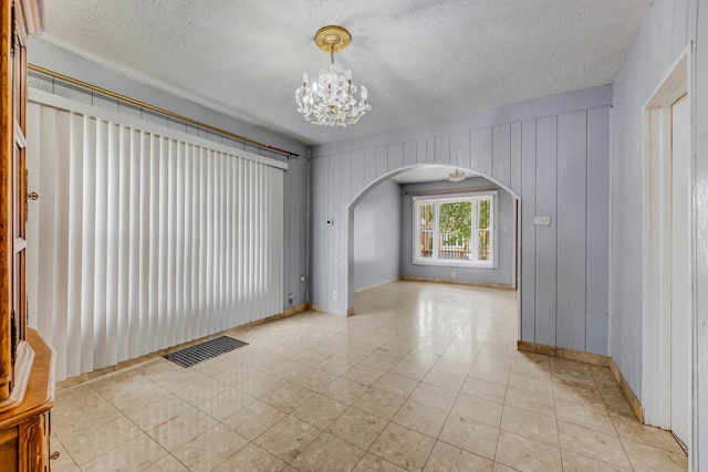 3928 W 63rd Pl, Chicago, IL 60629 - empty room with arched walkways, a chandelier, a textured ceiling, and light tile patterned flooring