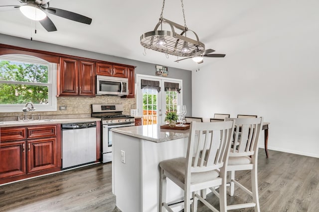 513 White Birch Rd, Lindenhurst, IL 60046 - kitchen with appliances with stainless steel finishes, a ceiling fan, wood finished floors, tasteful backsplash, and a kitchen bar