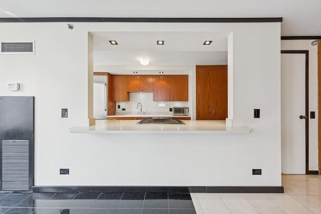 1230 N State Pkwy Unit 17A, Chicago, IL 60610 - kitchen featuring brown cabinetry, stainless steel appliances, light countertops, a peninsula, and light tile patterned floors
