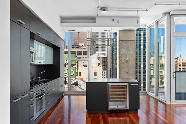 550 N Saint Clair St Unit 2301, Chicago, IL 60611 - kitchen featuring beverage cooler, a wall of windows, dark countertops, stainless steel appliances, and dark wood-type flooring