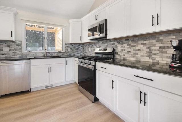 3302 Rustic Ln, Crown Point, IN 46307 - kitchen with stainless steel appliances, decorative backsplash, light wood-type flooring, white cabinets, and lofted ceiling