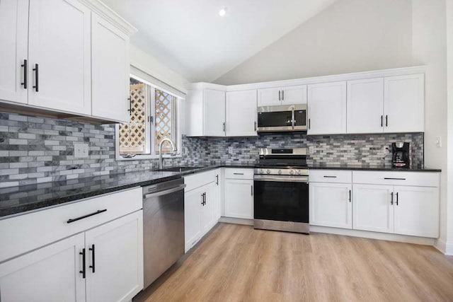 3302 Rustic Ln, Crown Point, IN 46307 - kitchen with stainless steel appliances, vaulted ceiling, white cabinets, light wood-style floors, and backsplash