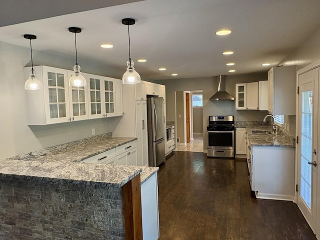 214 Tiverton Rd, Kankakee, IL 60901 - kitchen with appliances with stainless steel finishes, wall chimney exhaust hood, light stone counters, a peninsula, and glass insert cabinets